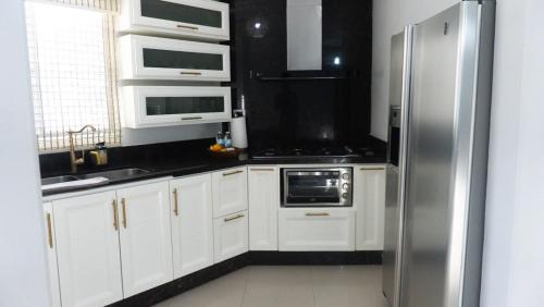 a kitchen with white cabinets and a stainless steel refrigerator at Valle Bonito in Los Mochis