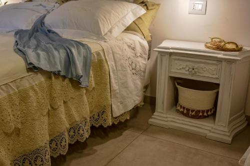 a bed with a white nightstand next to a bed with pillows at Antica Casina B&B di Charme in Pulsano
