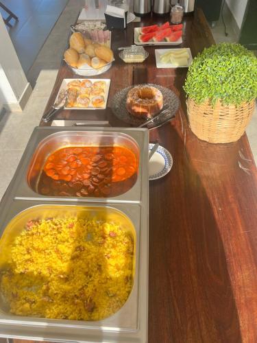 een tafel met dienbladen van verschillende soorten levensmiddelen bij Pousada Ibiza in Pirenópolis