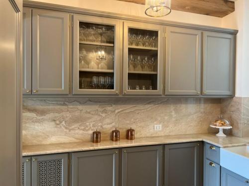 a kitchen with gray cabinets with glasses in it at Luxury in Lake Como in a 5 bed lake front home in Valmadrera