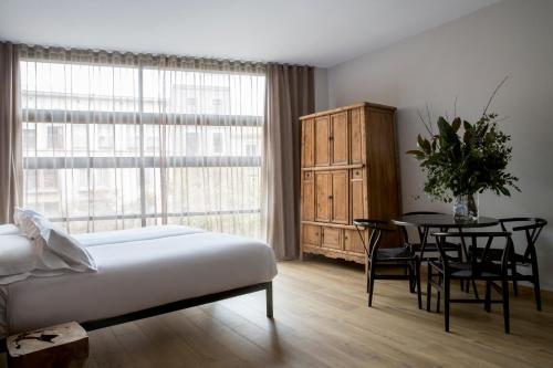 a bedroom with a bed and a table and a window at Aparthotel Allada 3* in Barcelona