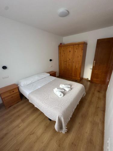 a bedroom with a bed with white sheets and wooden floors at Apartamento La brisa Fiscal in Fiscal