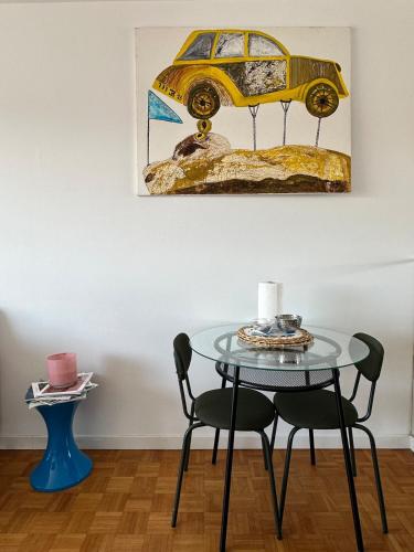 une table avec deux chaises et une peinture d'une voiture jaune dans l'établissement New apartment with panoramic view, à Marseille