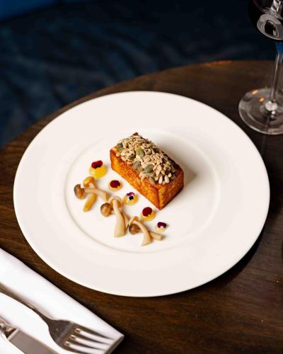 a white plate with a piece of food on a table at Kimpton Fitzroy London by IHG in London
