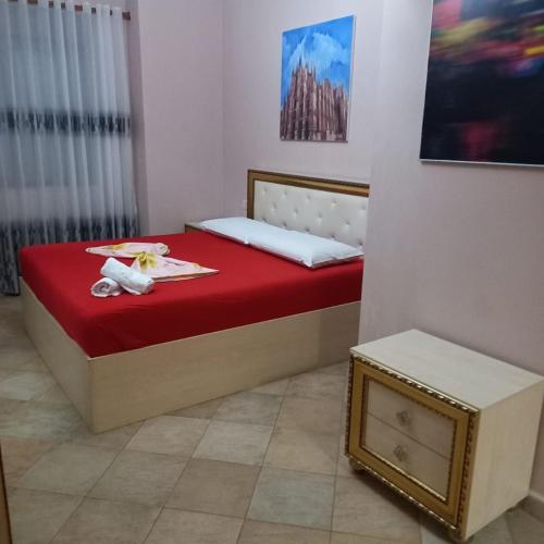 a bedroom with a bed with a red mattress and a table at Golden Apartment in Tirana