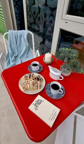 a red table with plates and cups of coffee on it at Apartada Orilla Loft in Camarma de Esteruelas