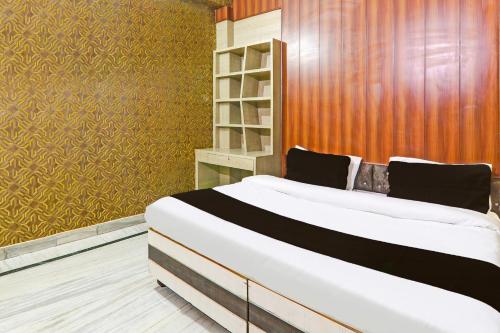 a bedroom with a large white bed and a wooden wall at Hotel O S&R Haven in Kānpur