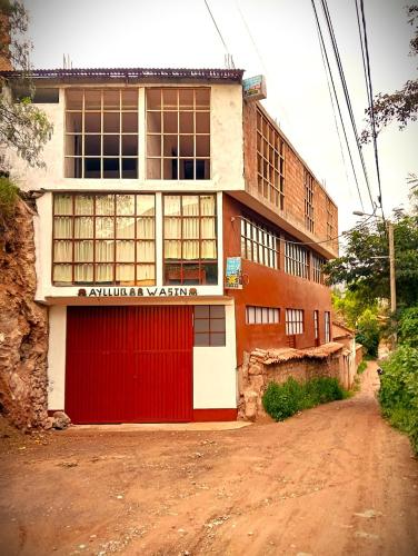 a building with a red door on a dirt road at Guest House Aylluq Wasin in Urubamba