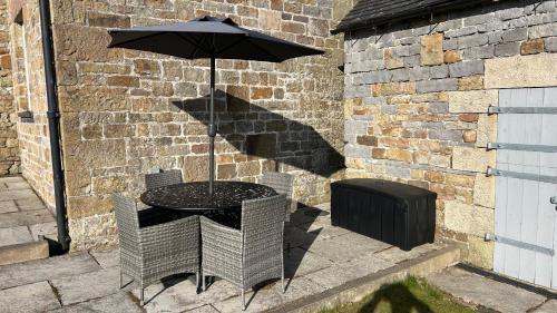 a table with an umbrella in front of a brick wall at Stunning 4 Bed Near Alton Towers, Polar Bears, Peak District in Waterfall