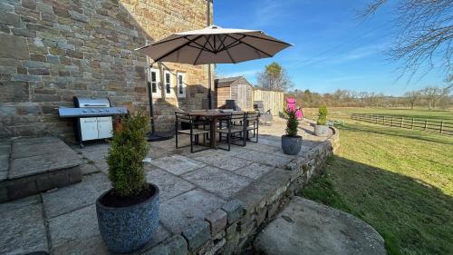 a patio with a table and an umbrella at Stunning 4 Bed Near Alton Towers, Polar Bears, Peak District in Waterfall