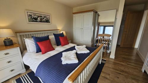 a bedroom with a bed with blue and red pillows at Chupra in Saint Mawes