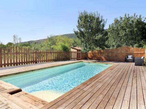 une piscine avec une terrasse en bois à côté d'une clôture dans l'établissement Gîte Les Courtines, à Saint-Privat