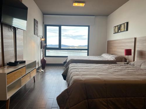 a hotel room with two beds and a large window at Gray Fox Apartments - Marina in Ushuaia