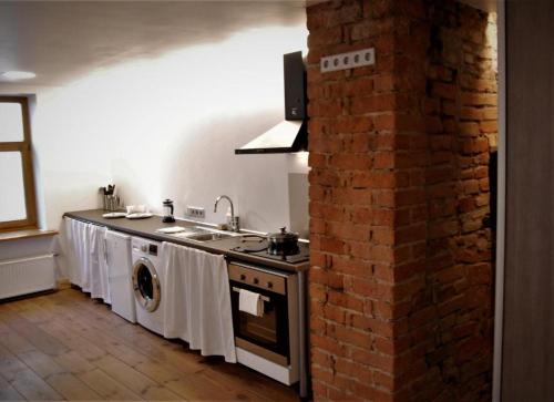 a kitchen with a stove top oven next to a brick wall at Amber Private Rooms in Rīga