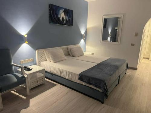 ein Schlafzimmer mit einem Kingsize-Bett und einem Stuhl in der Unterkunft Domina Coral Bay Sultan Tre in Sharm El Sheikh