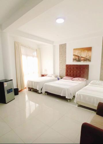 a room with three beds and a tv in it at Deluxe Hotel Talara in Talara
