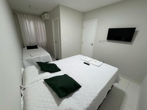 two beds with green pillows in a white room at Casa Arruda Climatizada 2 in Vitória da Conquista