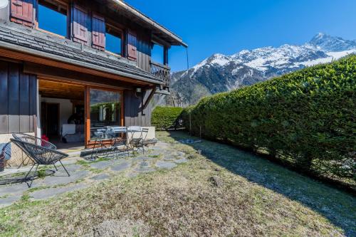une maison avec une terrasse et des montagnes en arrière-plan dans l'établissement Chalet Grands Montets -Garden -Ski in out - Happy Rentals, à Chamonix-Mont-Blanc