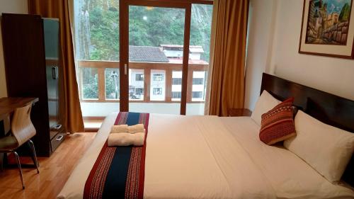 a bedroom with a large bed with a large window at El Quetzal MachuPicchu in Machu Picchu