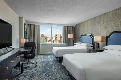 a hotel room with two beds and a flat screen tv at Sheraton LaGuardia East Hotel in Queens