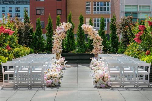 a row of white chairs in a garden with flowers at Sheraton LaGuardia East Hotel in Queens