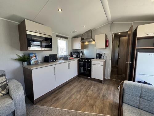 a kitchen with white cabinets and a stove top oven at Fantasy Island Holiday Park Eastgate - The Seasons with Hot Tub - Coastal Caravan Breaks in Ingoldmells
