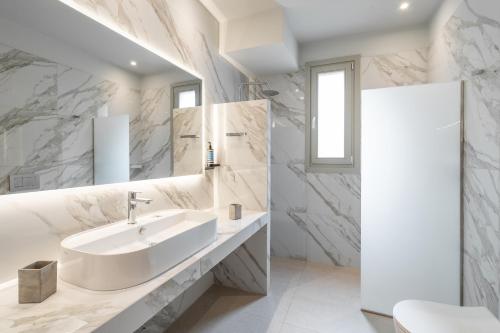 a white bathroom with a sink and a mirror at SuiteHome Villas with Private Pools by Explore Andros in Andros