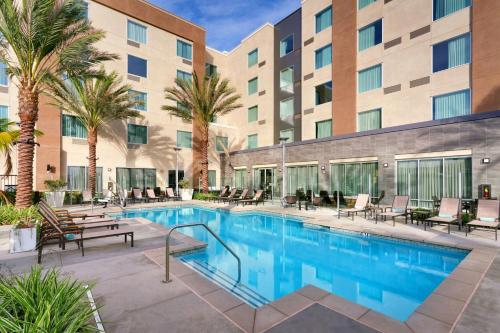 a pool at a hotel with chairs and palm trees at TownePlace Suites by Marriott Los Angeles LAX/Hawthorne in Hawthorne