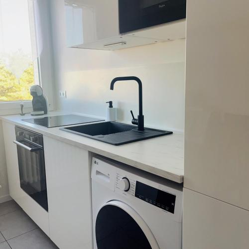 a white kitchen with a sink and a dishwasher at Appartement 5 Lits, tout équipé, WiFi, NetfliX in Vaulx-en-Velin