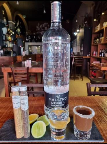 a bottle of alcohol sitting on a table with a glass at Hotel Plaza Queretaro in Querétaro