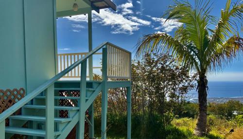 a staircase leading up to a blue house with a palm tree at Kailua Kona Overlook Suites in Kailua-Kona