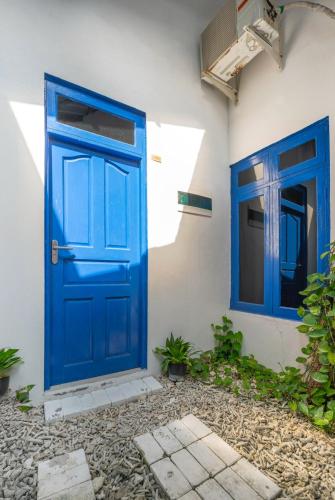 a blue door and two windows on a building at La Due Thulusdhoo in Thulusdhoo