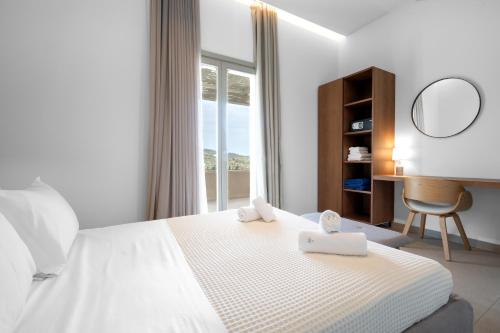 a bedroom with a white bed with a desk and a window at SuiteHome Villas with Private Pools by Explore Andros in Andros