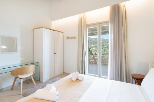a bedroom with a bed and a chair and a window at SuiteHome Villas with Private Pools by Explore Andros in Andros