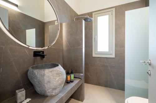 a bathroom with a large stone sink and a mirror at SuiteHome Villas with Private Pools by Explore Andros in Andros