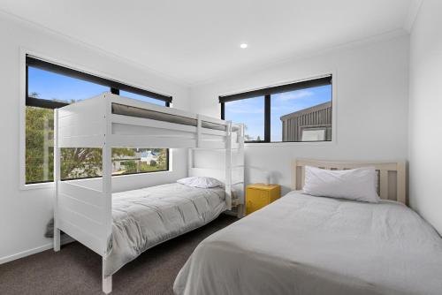 a bedroom with a bunk bed and two windows at Edinburgh Escape - Waihi Beach Holiday Home in Waihi Beach