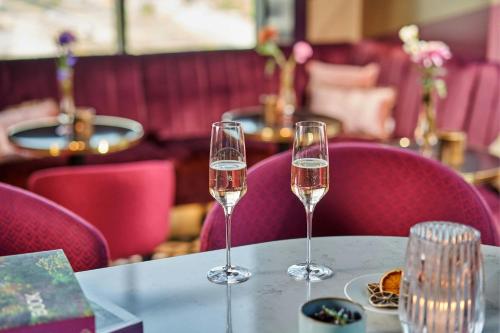 two glasses of champagne on a table in a restaurant at The Den, 's-Hertogenbosch, a Tribute Portfolio Hotel in Den Bosch