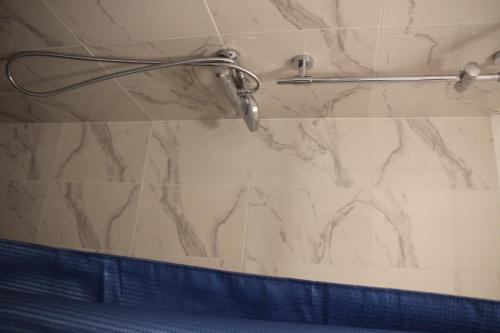 La salle de bains est pourvue d'une douche et d'un mur en marbre. dans l'établissement Saint-Martin's Inn, à Paris