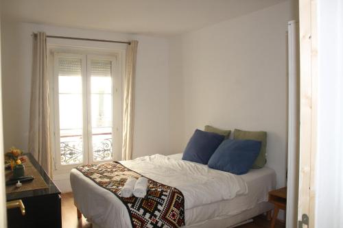 une chambre avec un lit avec des oreillers bleus et une fenêtre dans l'établissement Saint-Martin's Inn, à Paris