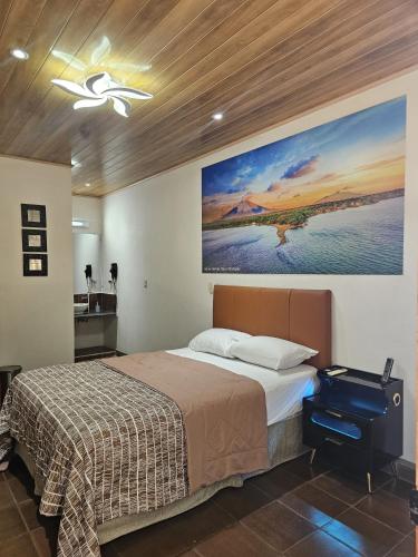 a bedroom with a bed and a painting on the wall at Nica Valley in Rivas