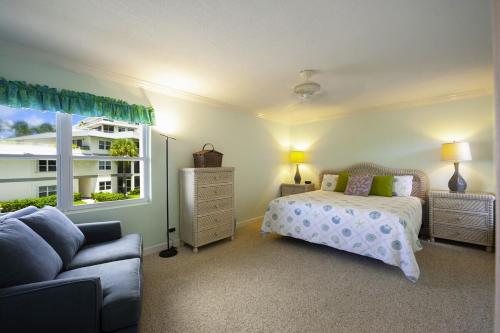 a bedroom with a bed and a couch and a window at Tamarind Bay # 16 in Grand Cayman