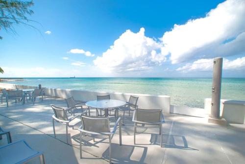 a patio with chairs and tables and the ocean at Tamarind Bay # 16 in Grand Cayman