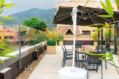 a patio with a table and chairs and an umbrella at Central Apartamentos Bogotá in Bogotá