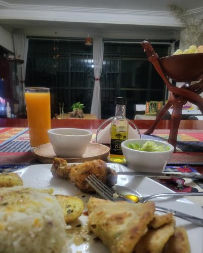 a table with a plate of food and a glass of orange juice at Aivilo Home in Kampala
