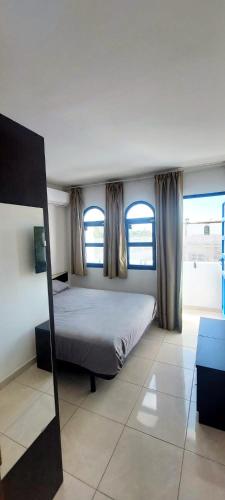 a bedroom with a bed and two windows at Maspalomas J&O in Maspalomas