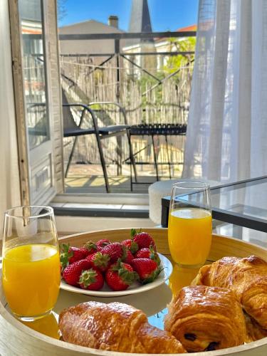 - un plateau de viennoiseries et de fruits sur une table avec du jus d'orange dans l'établissement Appartement élégant aux portes de Paris, à Bagnolet