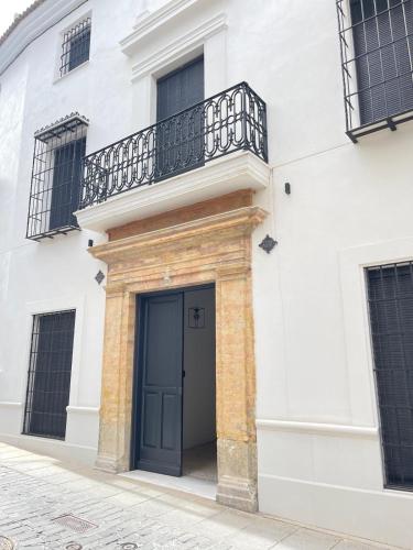 a white building with a blue door and a balcony at Casa Boutique Navarro in Montilla