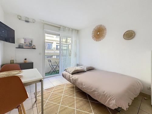 une chambre avec un lit, un bureau et une fenêtre dans l'établissement Studio calme avec balcon proche du port de Nice, à Nice