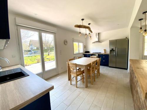 une cuisine avec une table et des chaises dans une pièce dans l'établissement La Dolce Vita familiale - 9 minutes des plages, à Bourseville