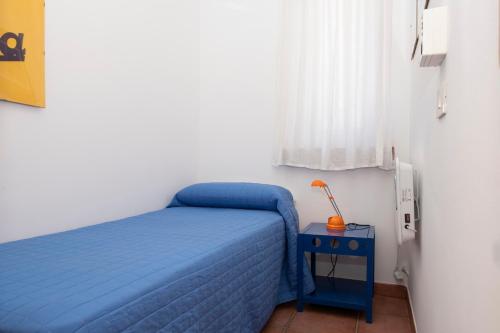 a small bedroom with a blue bed and a table at Casa Ponente con Vista Mare a Macari in Macari
